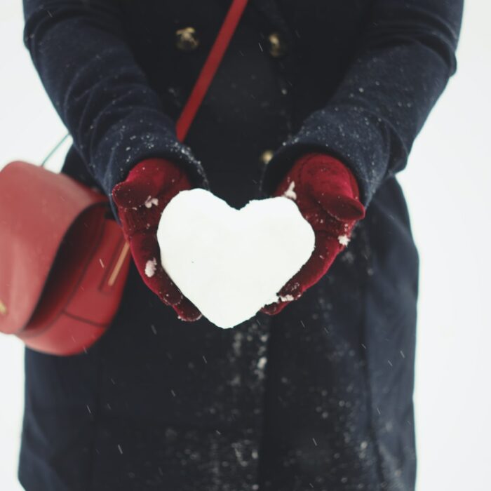 person holding heart-shaped snow