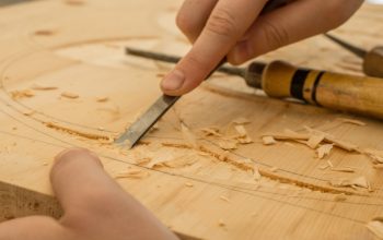 person using chisel while curving wood