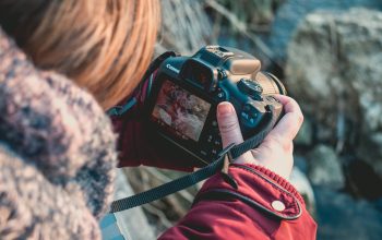 shallow focus photography of person using black Canon DSLR camera